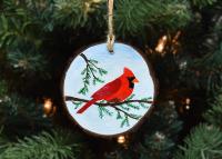 A wood slice ornament with a hand-painted northern cardinal in a cedar tree at www.covecreekphotography.com.