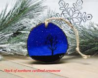 A deep blue starry night with a silhouette of birds perched in a tree is hand-painted on a wood slice ornament at Cove Creek Photography.