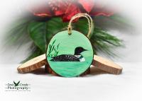 A hand-painted common loon on a pond wood slice ornament available for purchase at Cove Creek Photography.