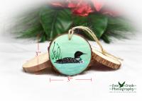 A hand-painted wood slice ornament with a common loon and size dimensions.