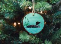 A rustic wood slice ornament with a hand-painted common loon and available at covecreekphotography.com.