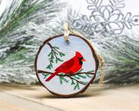 A bright red northern cardinal hand-painted on a wood slice at Cove Creek Photography.