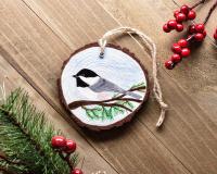 An acrylic painting of a Carolina chickadee on a three inch wood slice at Cove Creek Photography.