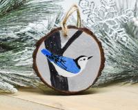 A hand-painted white-breasted nuthatch in the snow on a wood slice at Cove Creek Photography.
