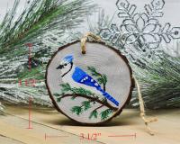 A hand-painted blue jay on a wood slice Christmas ornament with size measurements for scale at Cove Creek Photography.