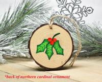 The holly leaves with three red berries hand-painted on the back of a handmade northern cardinal ornament at Cove Creek Photography.
