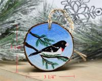 A hand-painted male rose-breasted grosbeak wood slice Christmas ornament with measurements displayed at covecreekphotography.com.