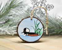 An acrylic painting of a male hooded merganser on a wood slice ornament at covecreekphotography.com.