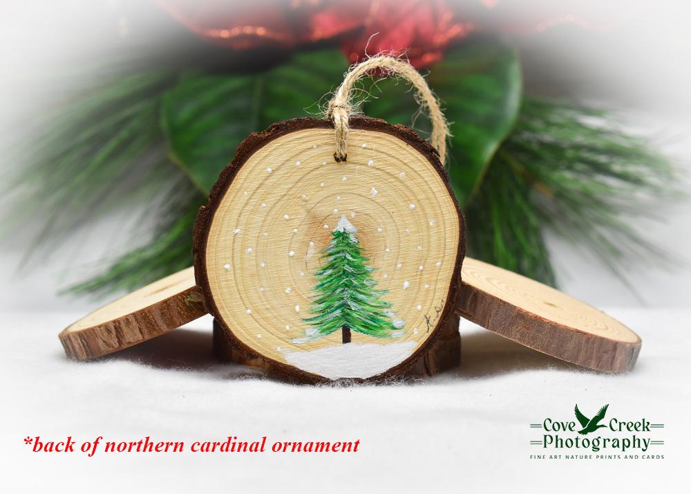An evergreen tree in snow on the back of a northern cardinal ornament that can be found at Cove Creek Photography.