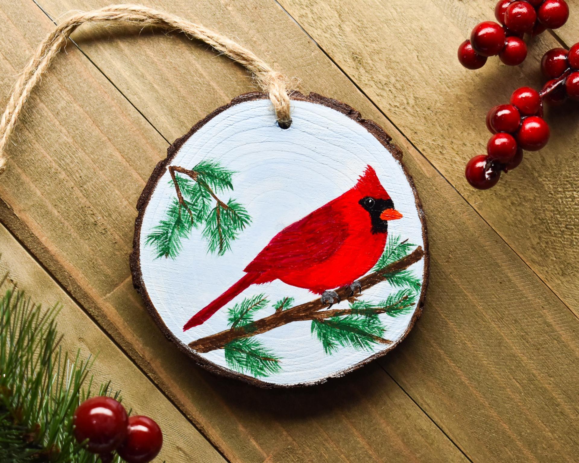 A wood slice Christmas ornament with a hand-painted northern cardinal available at Cove Creek Photography.