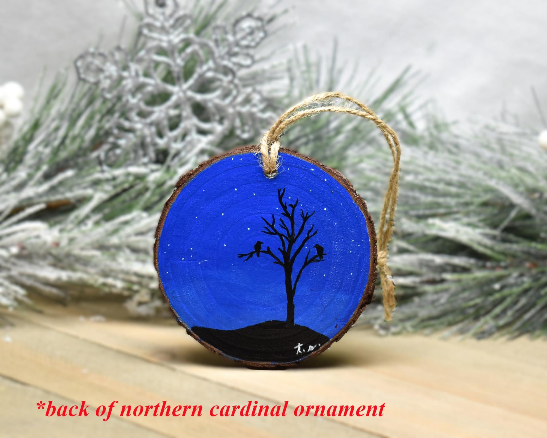 A painting on a wood slice of a starry night sky and black silhouettes at Cove Creek Photography.