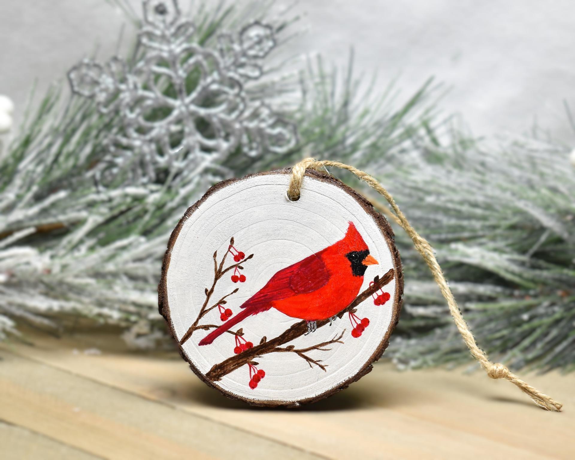 An acrylic painting on a wood slice of a cardinal on a tree branch with red berries at covecreekphotography.com.