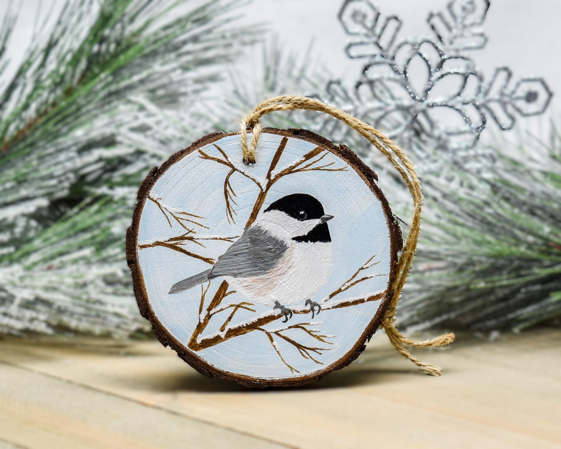 A Carolina chickadee hand-painted on a winter scene wood slice ornament at Cove Creek Photography.
