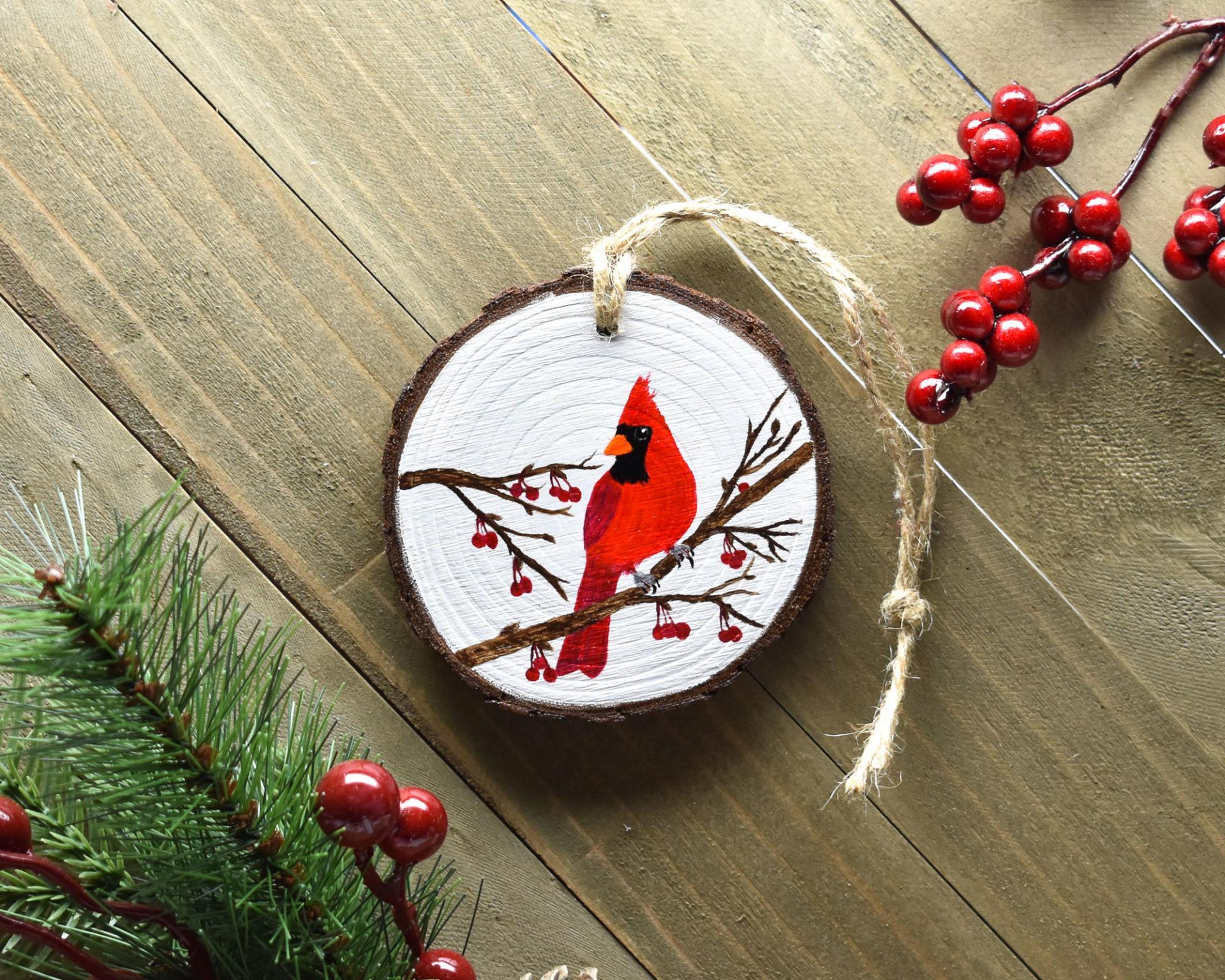 A display of an acrylic painting of a northern cardinal hand-painted on a wood slice ornament at Cove Creek Photography.