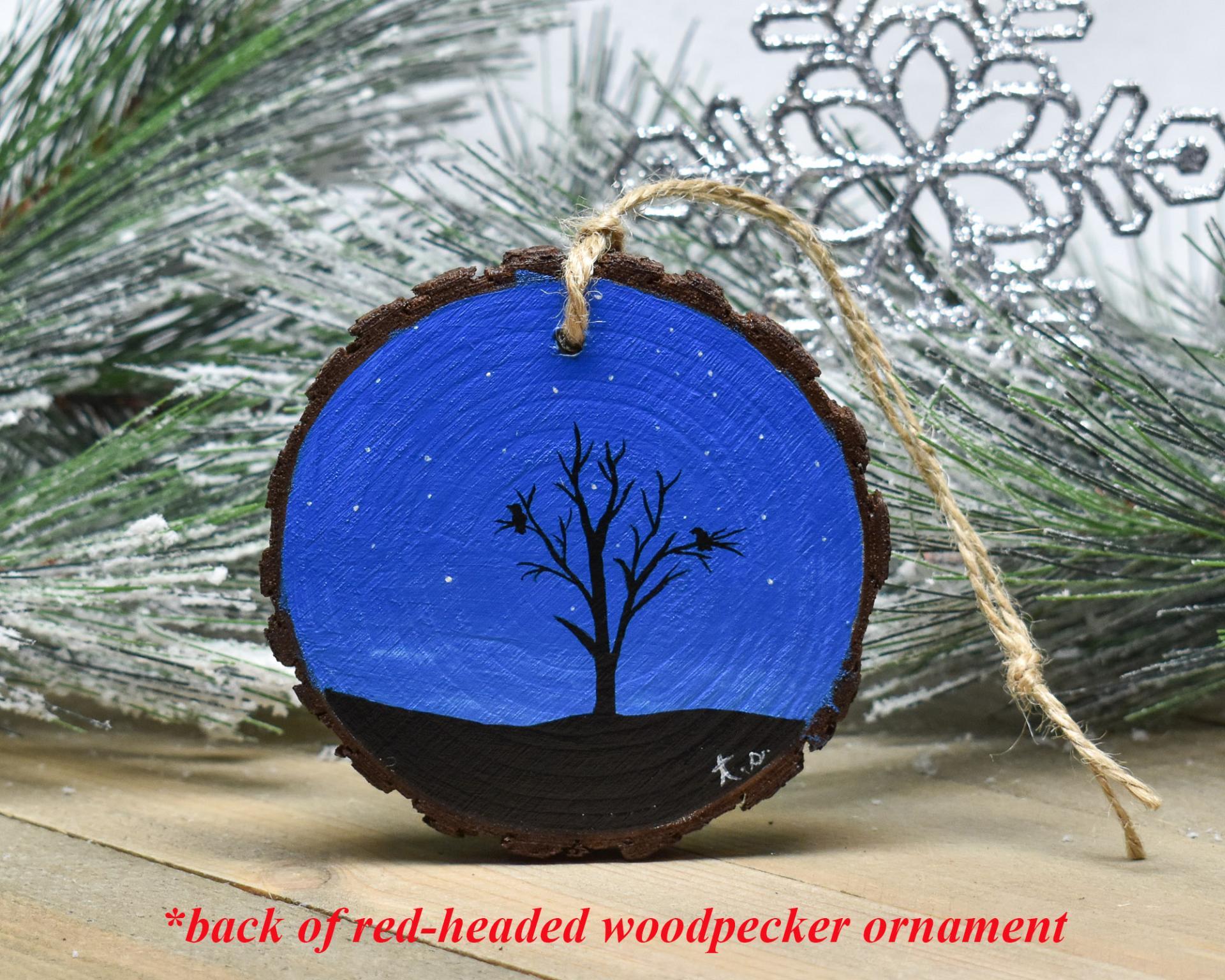 A hand-painted starry night with a silhouette of birds in a tree on a wood slice Christmas ornament at covecreekphotography.com.