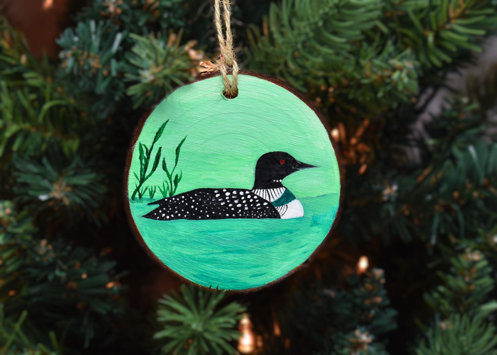 A hand-painted common loon on an ornament hanging on a Christmas tree available at Cove Creek Photography.