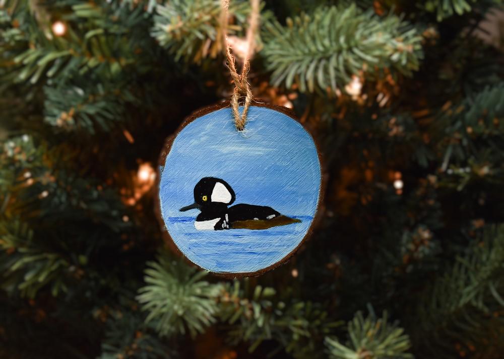 A hand-painted wood slice Christmas ornament with a hooded merganser available at Cove Creek Photography.