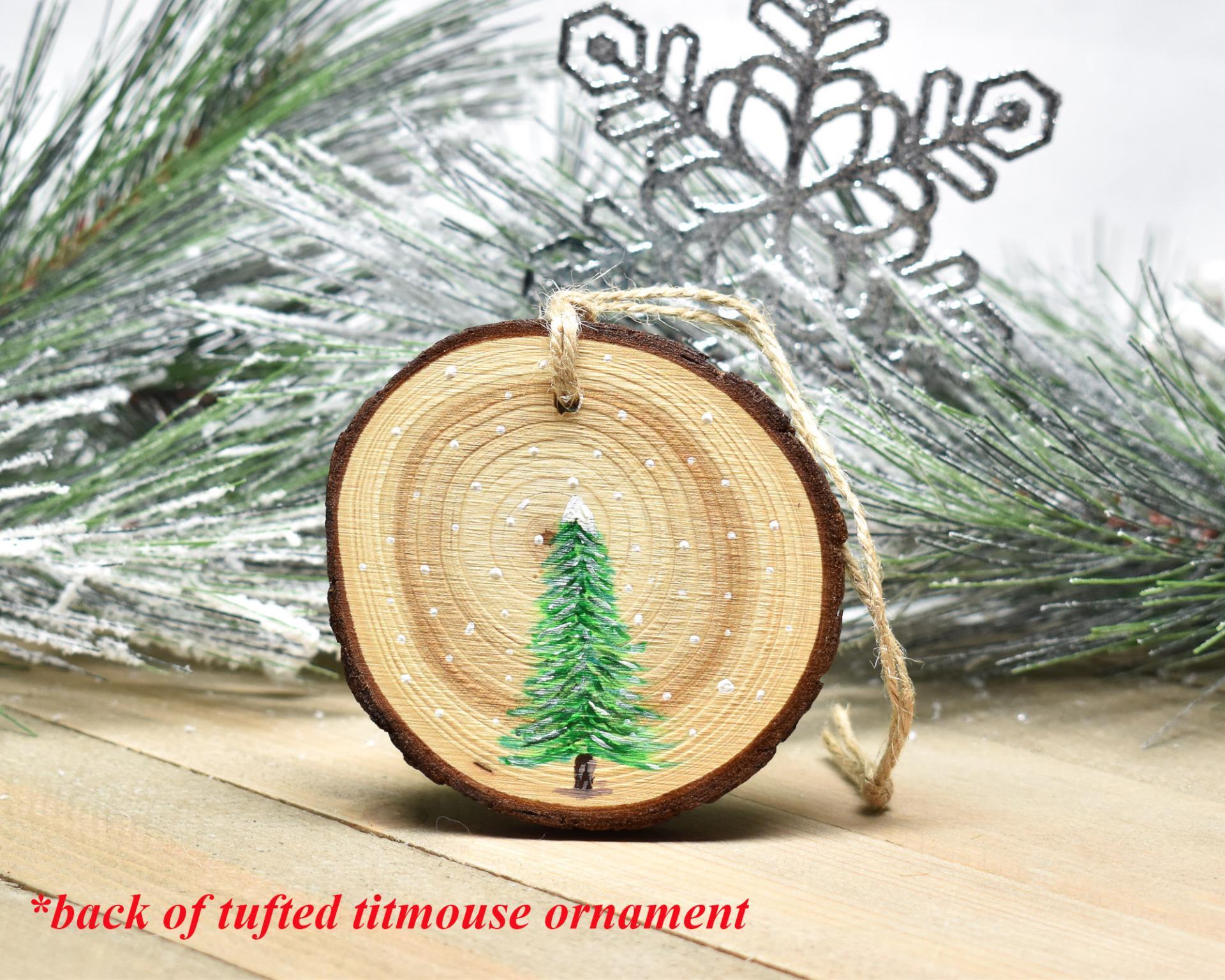An evergreen tree hand-painted on the back of a tufted titmouse wood slice ornament at covecreekphotography.com.