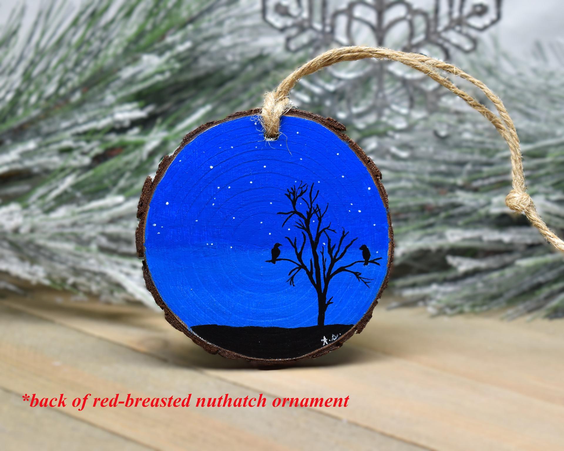 A wood slice ornament with a dark starry sky and a silhouette of birds roosting in a tree at Cove Creek Photography.
