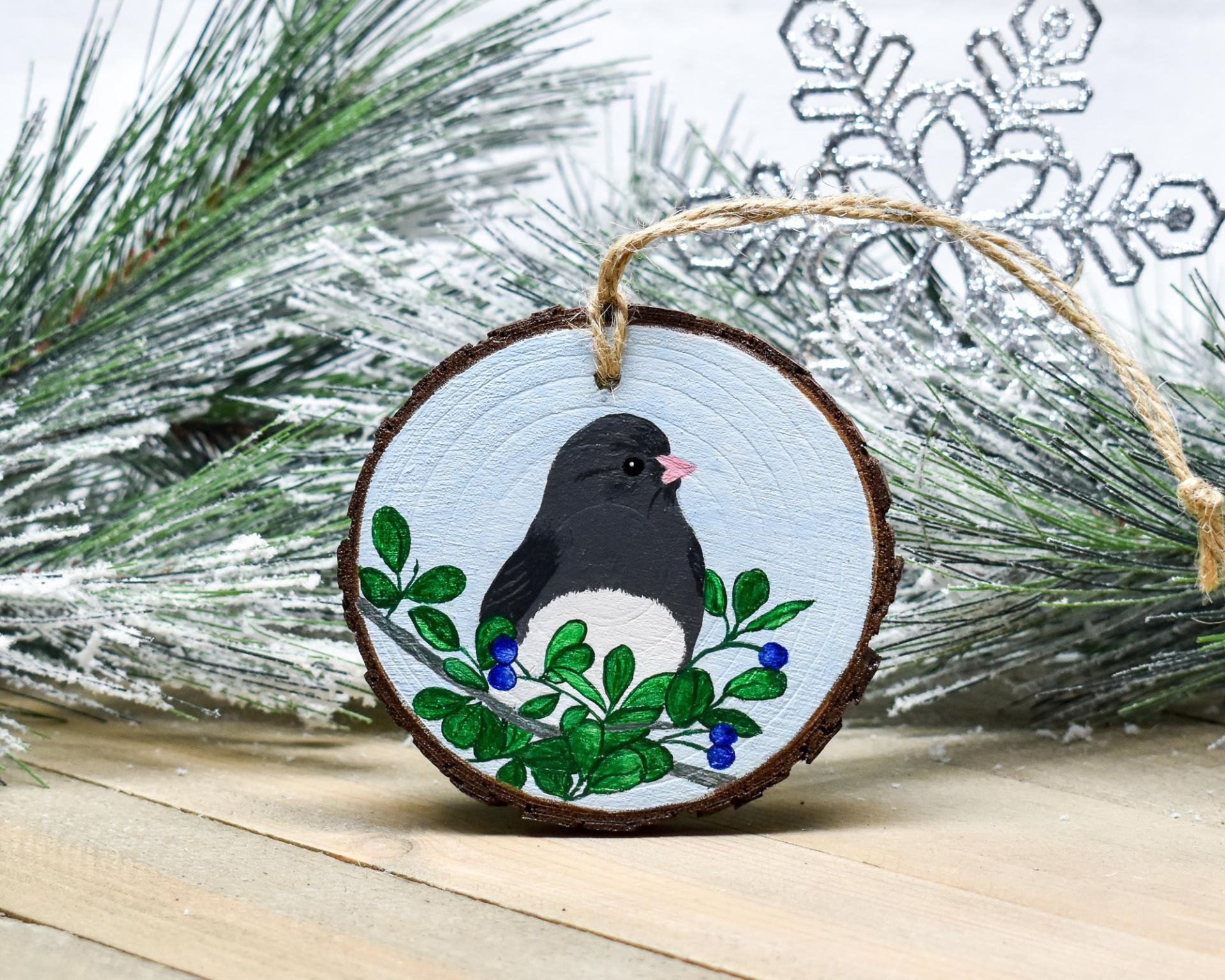 An acrylic painting of a dark-eyed junco on a wood slice ornament at covecreekphotography.com.