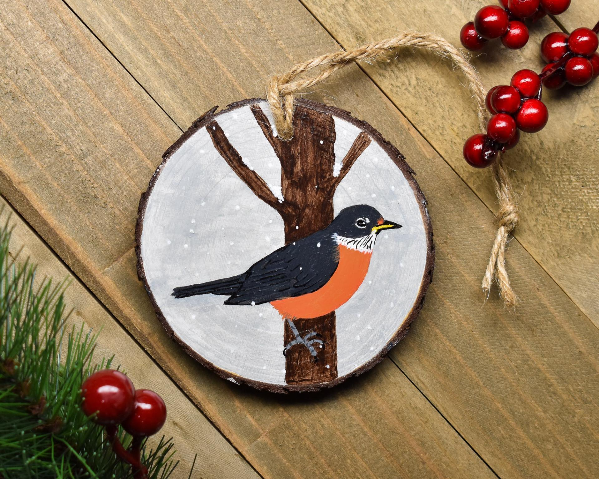 A handmade wood slice Christmas ornament with a hand-painted American robin at covecreekphotography.com.