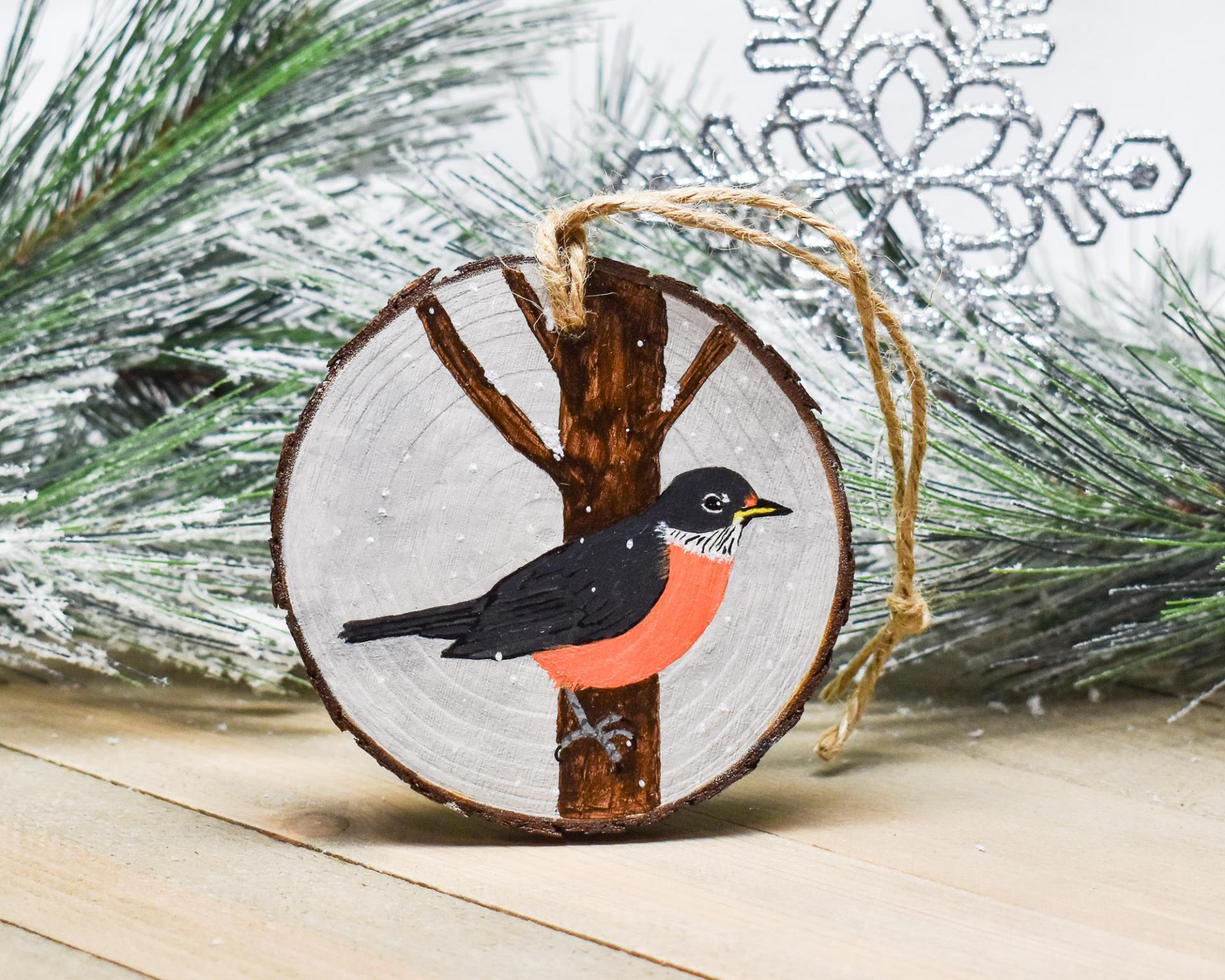 A hand-painted American robin in the snow wood slice Christmas ornament at Cove Creek Photography.