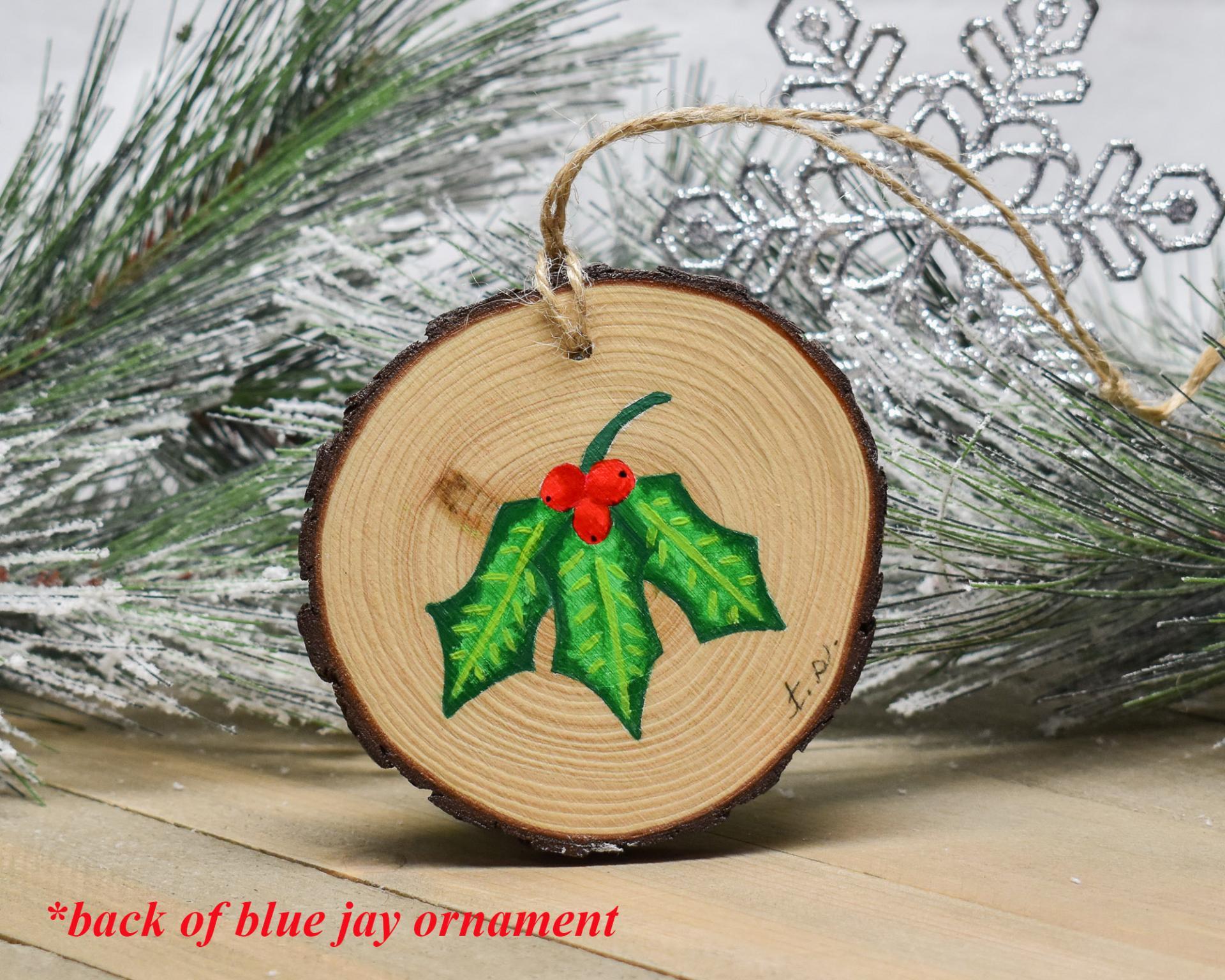 Hand-painted holly leaves with red berries hand-painted on the back of a wood slice ornament at covecreekphotography.com.