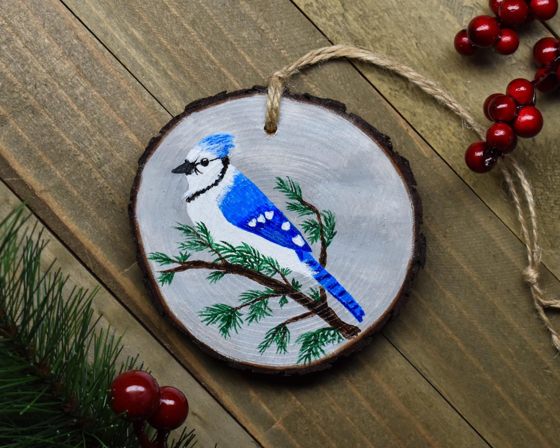 A handmade wood slice ornament with a hand-painted blue jay at covecreekphotography.com