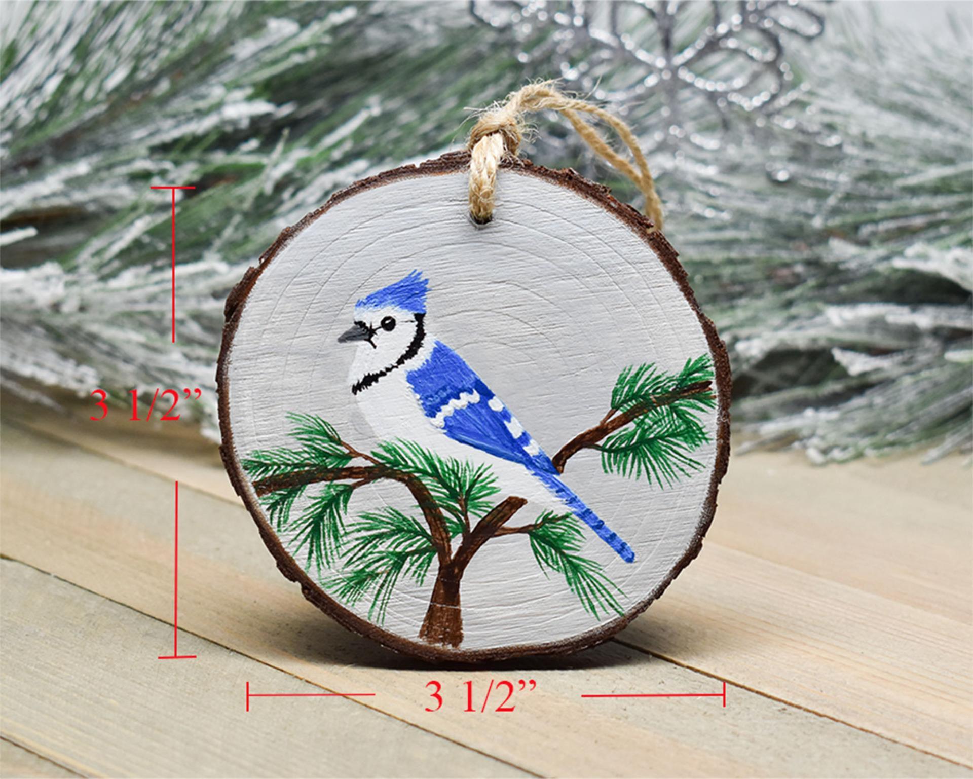 An image of a hand-painted blue jay wood slice Christmas ornament with the 3.5 inch diameter displayed in red on each side of the ornament.