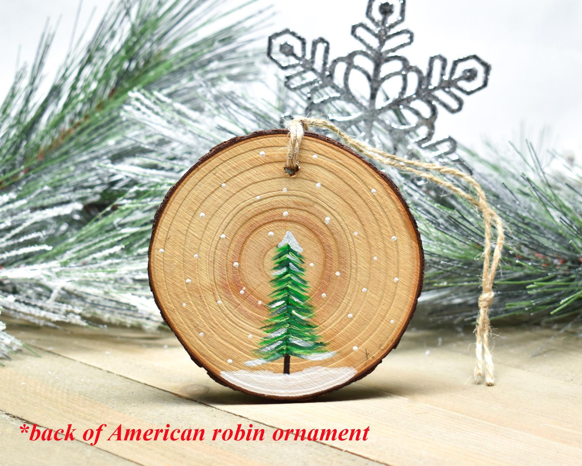 A simple rendering of a hand-painted evergreen tree on a wood slice ornament at Cove Creek Photography.