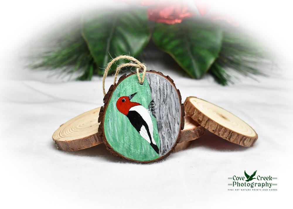 A wood slice ornament with a hand-painted tree and red-headed woodpecker at covecreekphotography.com.